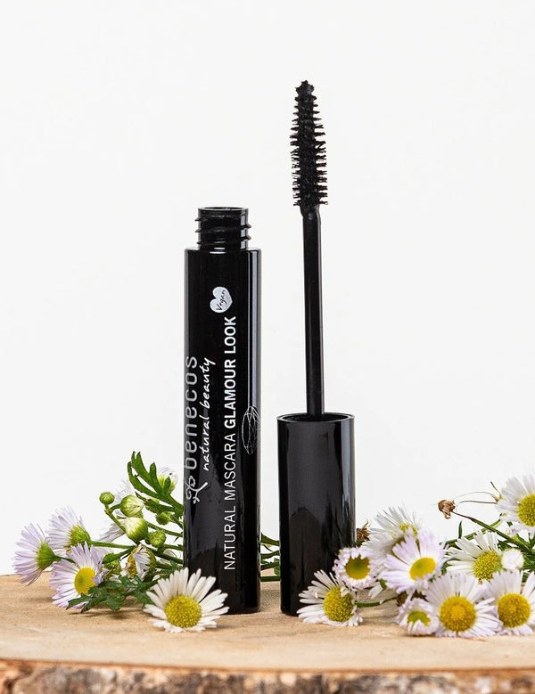Benecos Glamour Look Ultimate Black Mascara tube and open wand displayed among fresh white daisies.