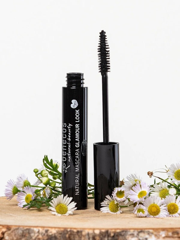Benecos Glamour Look Ultimate Black Mascara tube and open wand displayed among fresh white daisies.