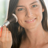 Model applying Benecos Natural Mineral Powder to her cheek with a large face brush.
