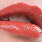 Close-up of lips wearing a warm coral shade of Benecos Natural Lipstick.