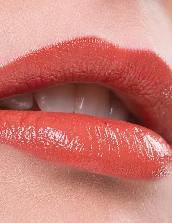 Close-up of lips wearing a warm coral shade of Benecos Natural Lipstick.