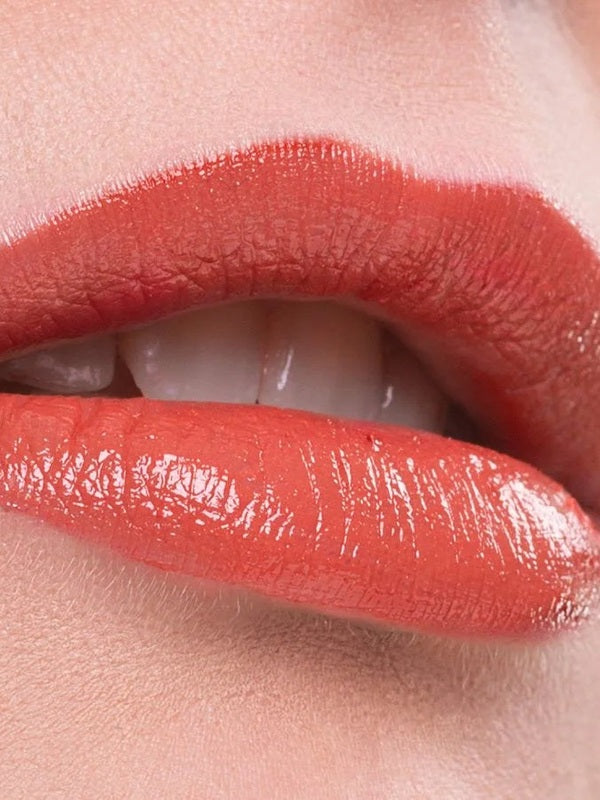 Close-up of lips wearing a warm coral shade of Benecos Natural Lipstick.