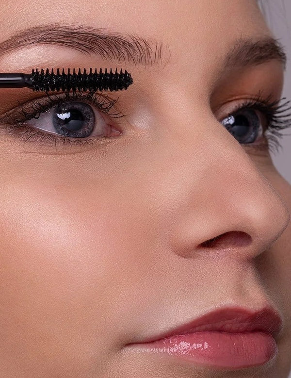 Close-up of a model applying Benecos Super Long Lashes Mascara in Carbon Black to her upper lashes.