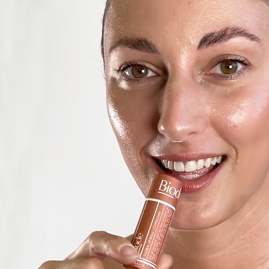 Model applying Biode Copper Daisy Tinted Lip Balm