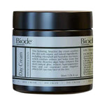 Dark amber Biode Day Cream jar with a wide black screw lid and a pale blue-grey label divided into panels of black text.