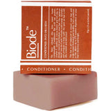 Dusty pink rectangular Biode Into the Earth conditioner bar beneath a terracotta carton printed with white lines and lettering.