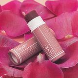 Two Biode Lip & Cheek Tinted Balm tubes in Lilly Pilly arranged on vivid pink flower petals.