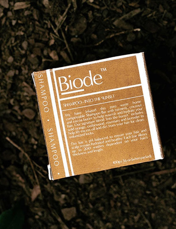 Biode Into The Sunset Shampoo Bar packaging resting on a dark natural ground, showing the back label and product details.