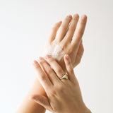 Close-up of hands spreading white cleanser foam over the back of a hand, demonstrating the lather of Biologi Bc Refresh Cleanser.