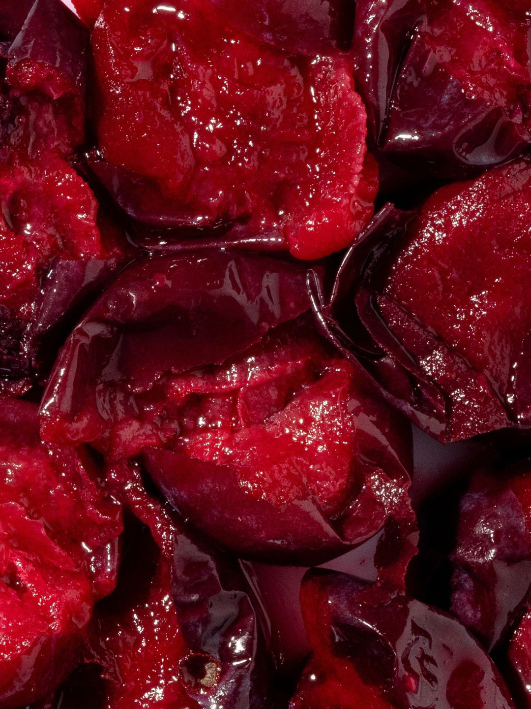 Close-up of deep red and purple chopped Davidson plum fruit, the botanical ingredient in Biologi Bd Luminosity Face Serum.