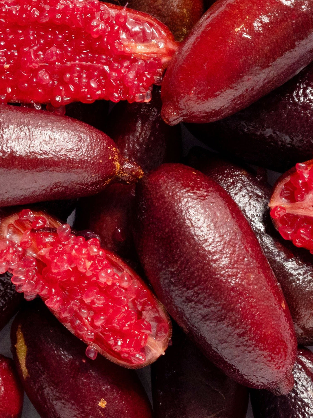 Close-up of dark red finger limes cut open to reveal their pink-red citrus pearls, the botanical ingredient image for Biologi Bl Nourish Lip Serum.