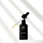 An open Biologi Br Rosehip Oil bottle stands on a white block beneath its raised glass dropper containing pale yellow oil, with soft diagonal shadows.