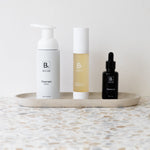 Biologi Bc Refresh Cleanser, Bf Restore serum and Br Rosehip Oil arranged together on a stone tray, showing the three products in a skincare routine.