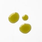 Three glossy golden-green drops of Biologi By Blackberry Seed Oil on a pale background, showing its colour and liquid texture.