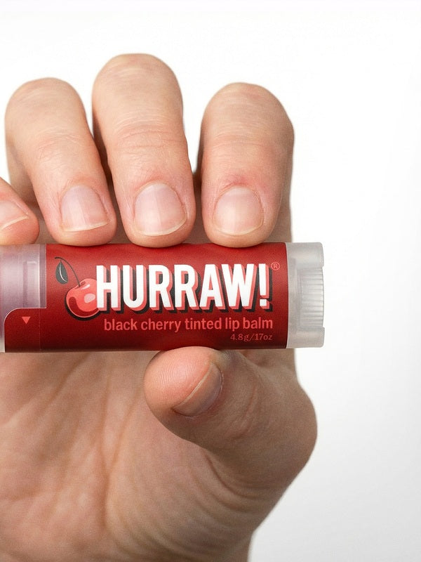 Hand holding Hurraw! Organic Lip Balm - Black Cherry 4.8g