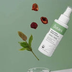White Botani Rescue Pore Refiner Essence bottle suspended diagonally above a glass beaker, with green leaves and dried red berries against a sage-green background.