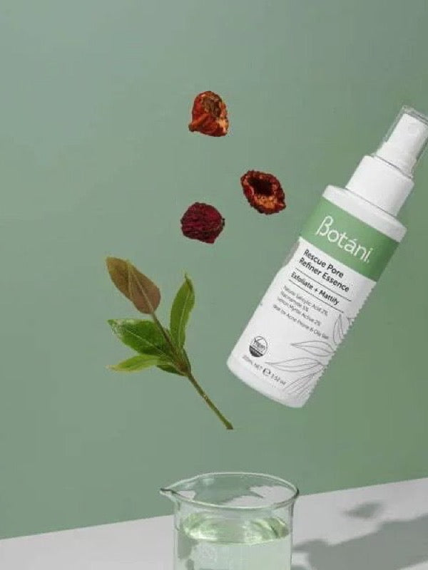 White Botani Rescue Pore Refiner Essence bottle suspended diagonally above a glass beaker, with green leaves and dried red berries against a sage-green background.
