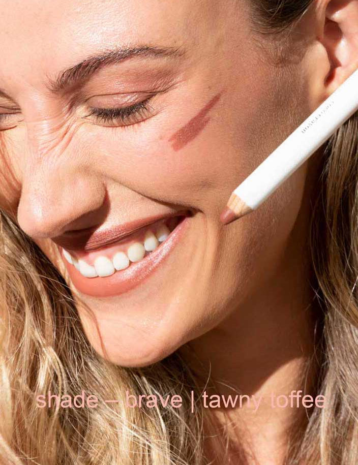 Woman applying makeup with a pencil, close-up of face.