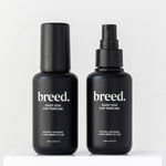 Two black Breed Daisy Dog Pup Perfume bottles displayed upright on a white plinth.