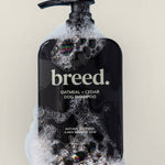 Breed Oatmeal & Cedar Dog Shampoo pump bottle covered with rich white foam.