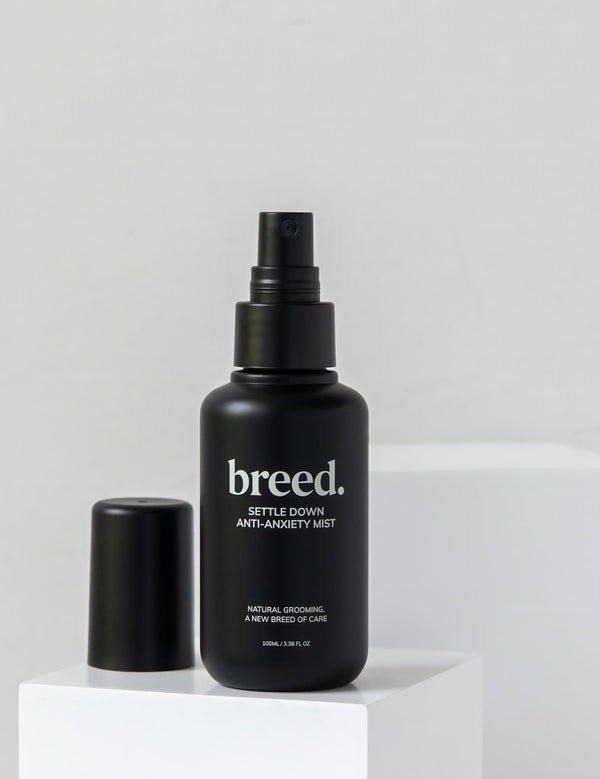 Breed Settle Down Anti-Anxiety Mist bottle and cap displayed on white studio plinths.