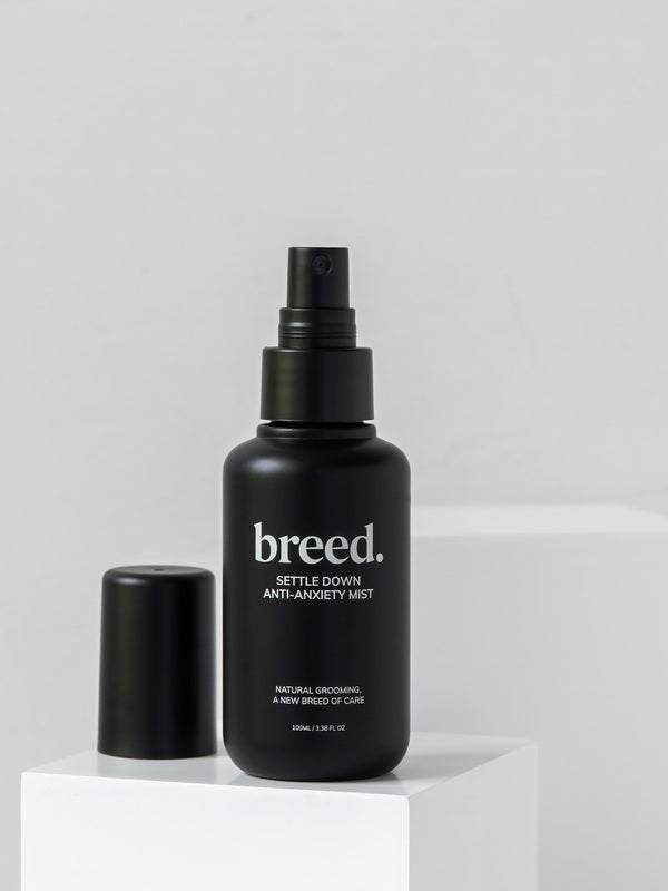 Breed Settle Down Anti-Anxiety Mist bottle and cap displayed on white studio plinths.