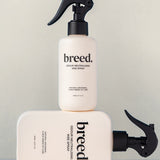 Two Breed Wee Spray Odour Neutralising bottles displayed upright and horizontally on a pale studio set.