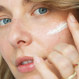 Woman applying a feather-shaped stroke of Ere Perez Moringa All-Beauty Creme to her cheek