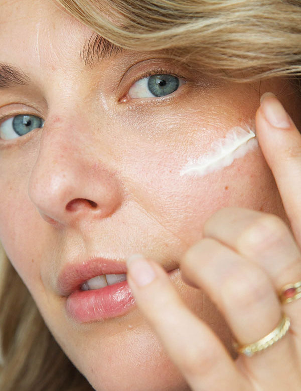 Woman applying a feather-shaped stroke of Ere Perez Moringa All-Beauty Creme to her cheek