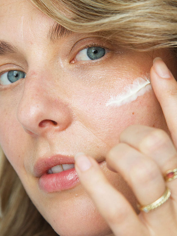Woman applying a feather-shaped stroke of Ere Perez Moringa All-Beauty Creme to her cheek
