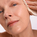 Woman wiping her cheek with a soft cloth while cleansing with Ere Perez Ginkgo Micellar Cleanser