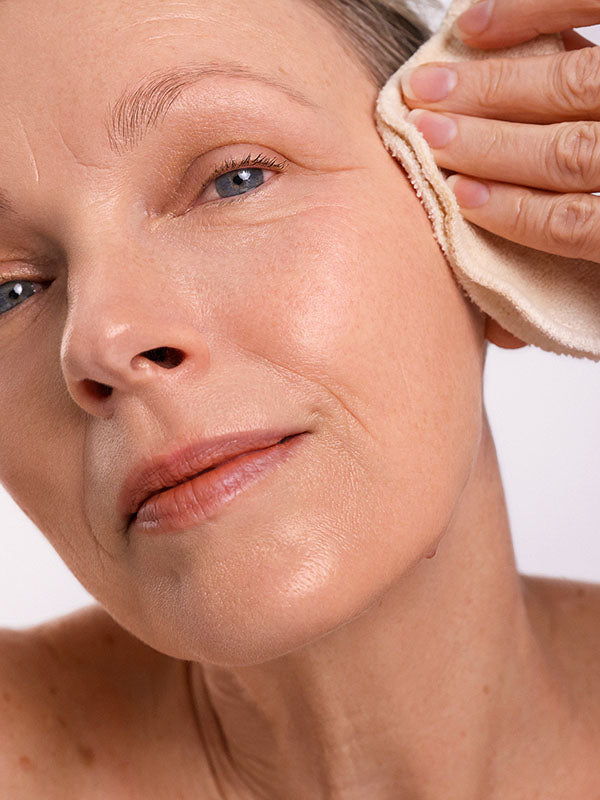 Woman wiping her cheek with a soft cloth while cleansing with Ere Perez Ginkgo Micellar Cleanser