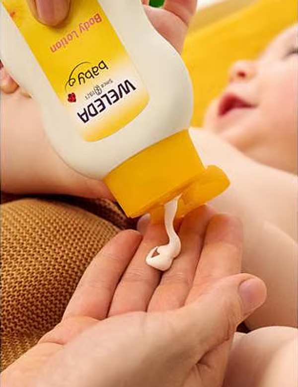 Weleda Calendula Body Lotion being dispensed before application to a baby.