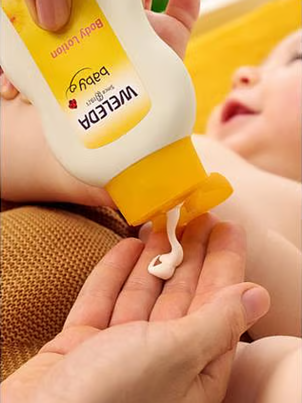 Weleda Calendula Body Lotion being dispensed before application to a baby.