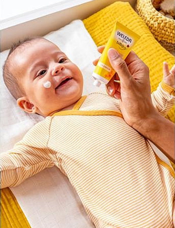 Applying Weleda Calendula Face Cream to baby's cheek