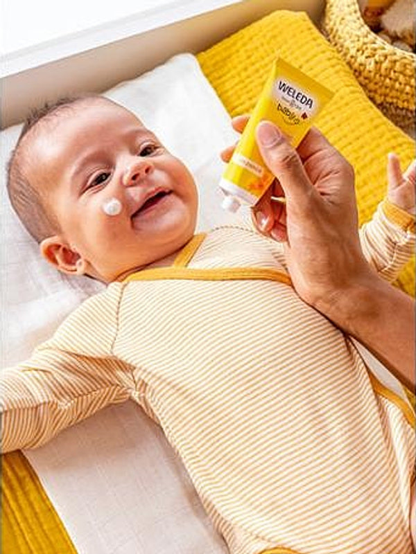 Applying Weleda Calendula Face Cream to baby's cheek