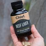 Hand holding CHIEF Organic Beef Liver Capsules outdoors