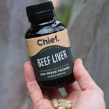 Hand holding CHIEF Organic Beef Liver Capsules outdoors