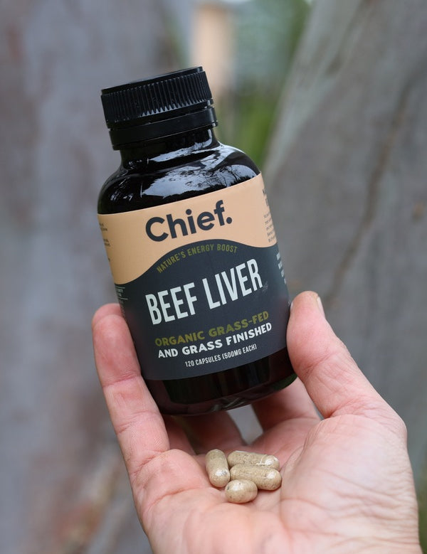 Hand holding CHIEF Organic Beef Liver Capsules outdoors