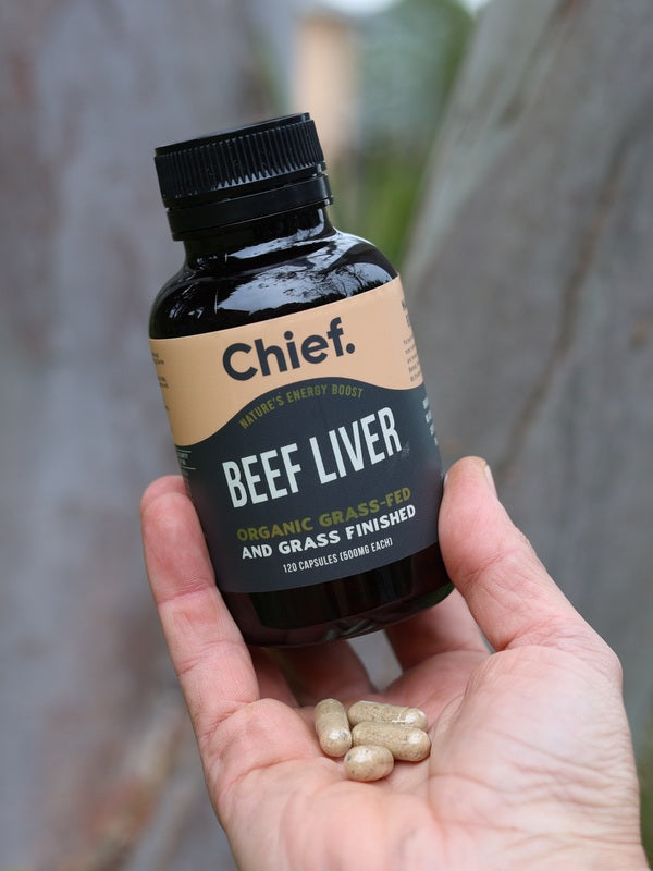 Hand holding CHIEF Organic Beef Liver Capsules outdoors