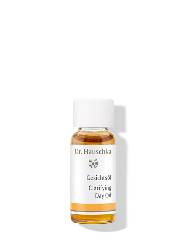 Small clear Dr Hauschka Clarifying Day Oil bottle filled with golden oil, with a white screw cap and white label with a yellow band.