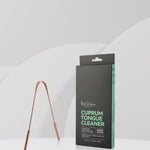U-shaped copper tongue scraper standing beside its tall black and mint-green carton on a white ledge against a pale grey background.