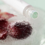 Ere Perez Grape Water Eye Serum rollerball frozen in ice with grapes on a mint background
