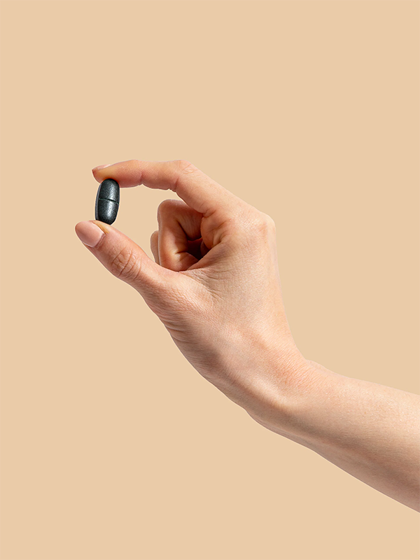 Hand holding a Herbs of Gold Magnesium Night tablet