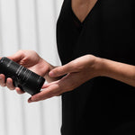 Woman in a black dress holding the Mukti Botanique Natural Deodorant Sandalwood and Sage