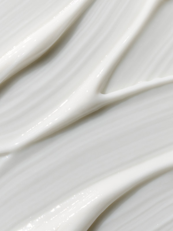 Extreme close-up of glossy white cream swept diagonally into smooth folds and narrow raised ridges.