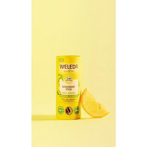 Deodorant Stick Citrus-Bergamot next to a slice of lemon, against yellow background.