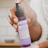 Hand spraying Dr. Bronner's Lavender Organic Hand Sanitiser onto the opposite palm.