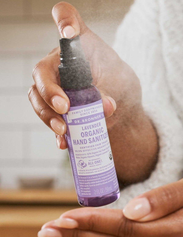 Hand spraying Dr. Bronner's Lavender Organic Hand Sanitiser onto the opposite palm.