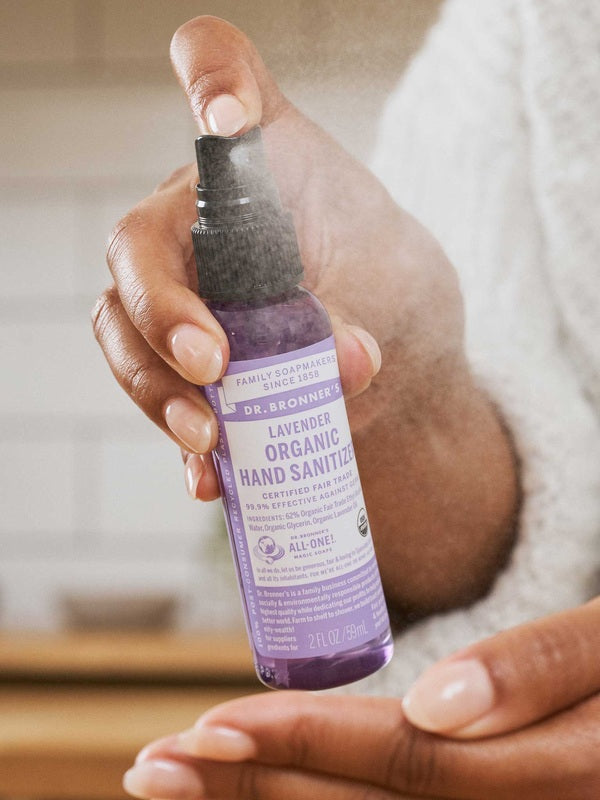 Hand spraying Dr. Bronner's Lavender Organic Hand Sanitiser onto the opposite palm.